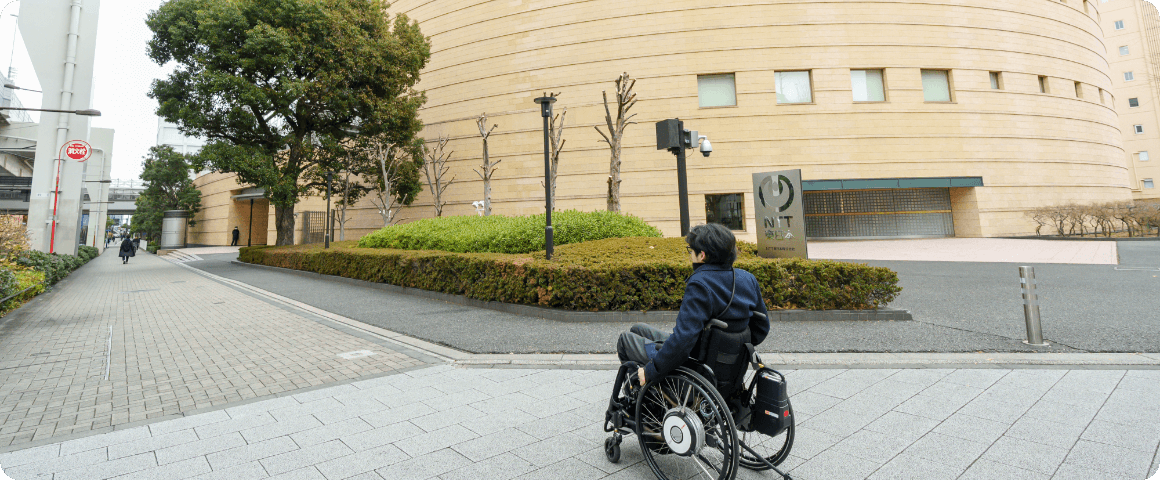 交差点を渡って左に曲がり、右側にNTT東日本本社ビルを見ながら進む様子